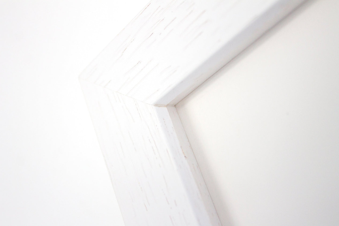 Close up detail of a white frame with woodgrain detail.