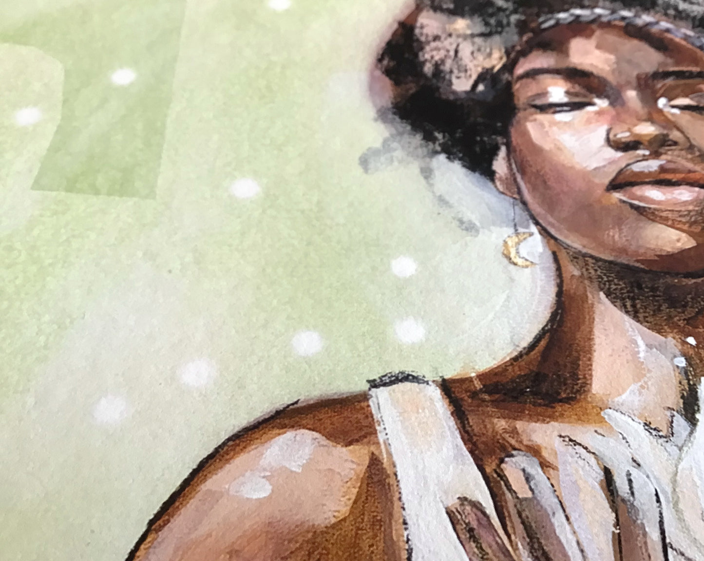 Close up detail of art print of an african woman with a moon earring holding a flower.