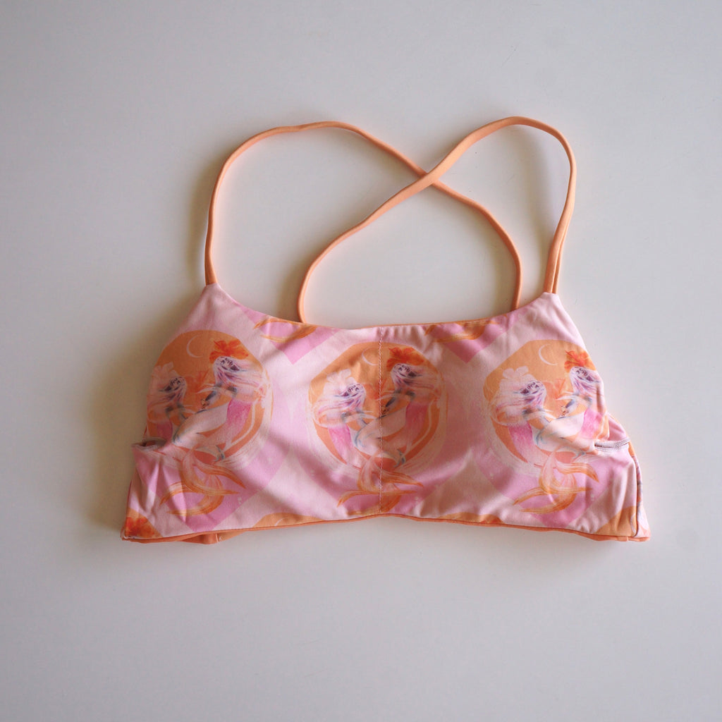 Flatlay of the Chasing Rivers x Hannah Chloe Calypso pink illustrated crop top featuring soft feminine artwork in peach and pink tones on a white background.