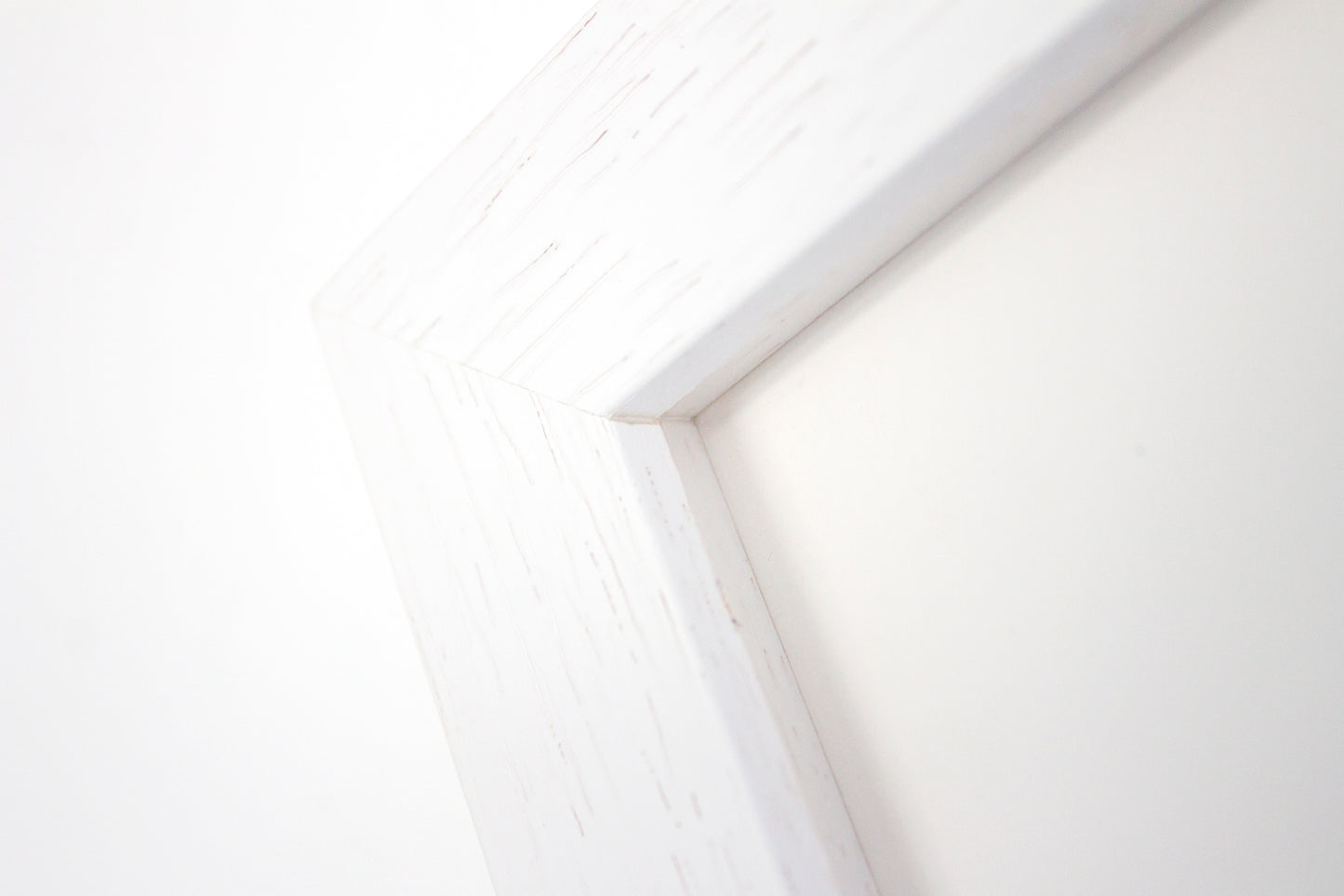 Close up detail of a white box frame with wood grain.
