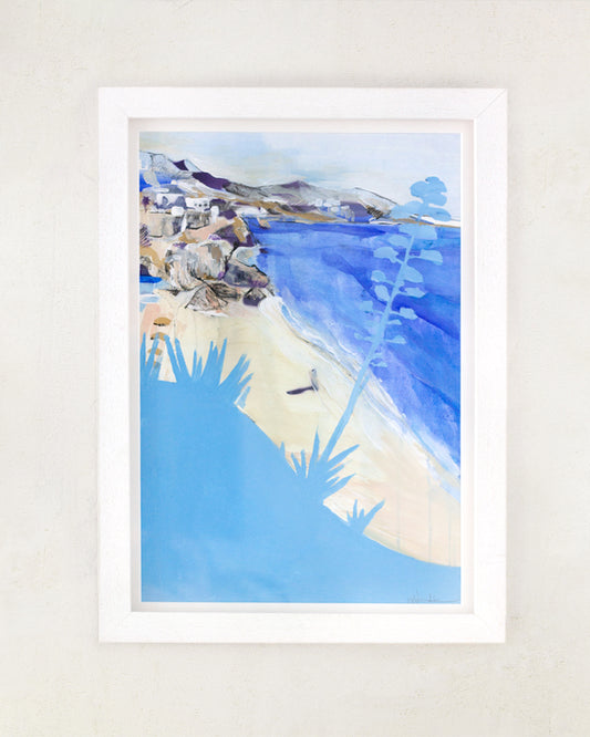 A painting of a beach scene with the sea, a white town algarve plants and a person walking on the shore. In bright blues. In a white frame on a white wall.