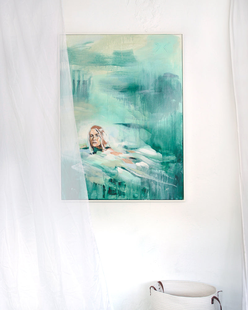 Painting of a swimmer in the sea in turquoise and green. In a Ibiza style interior with white walls a curtain and a basket.