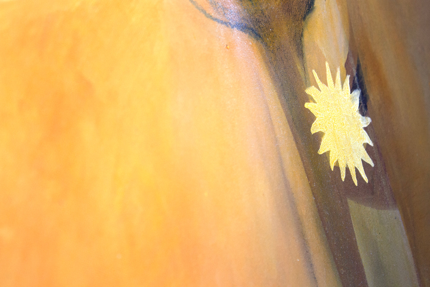Close up detail of a painting in an orange glow. A sun earring detail.
