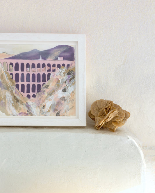 The landscape frames the aches of Nerva aqueduct painted in pastel tones. In an interior setting  with a desert rose.