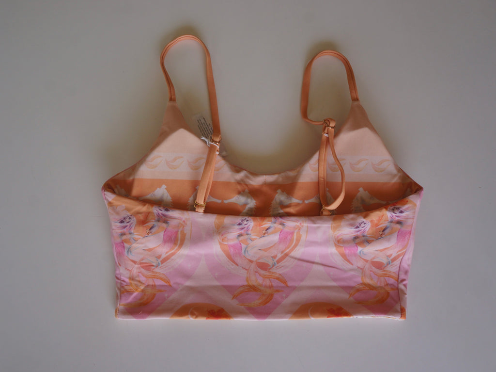 Flatlay of the back of the Chasing Rivers x Hannah Chloe Calypso pink illustrated crop top with adjustable straps and soft peach and pink artwork.