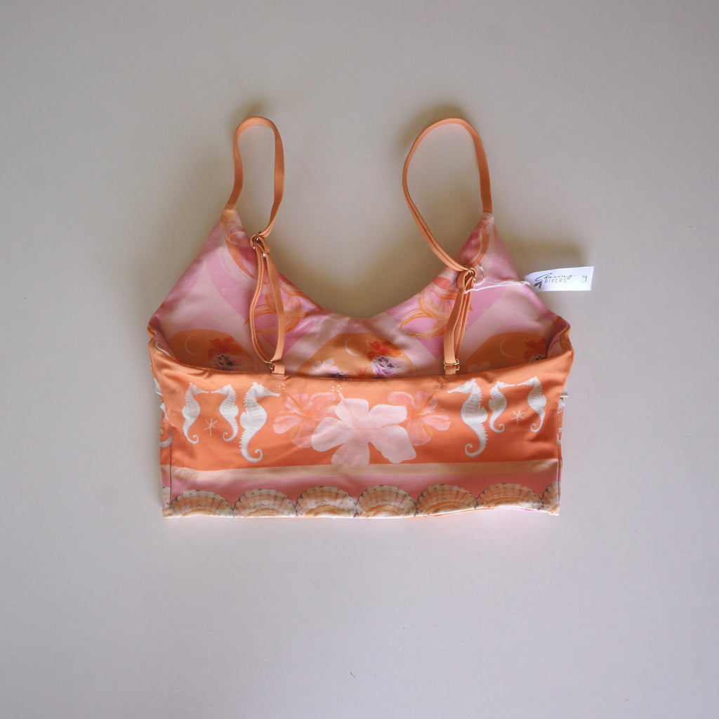 Flatlay of the back of the Chasing Rivers x Hannah Chloe Calypso crop top featuring a peach seahorse print, floral artwork, and adjustable straps on a white background.