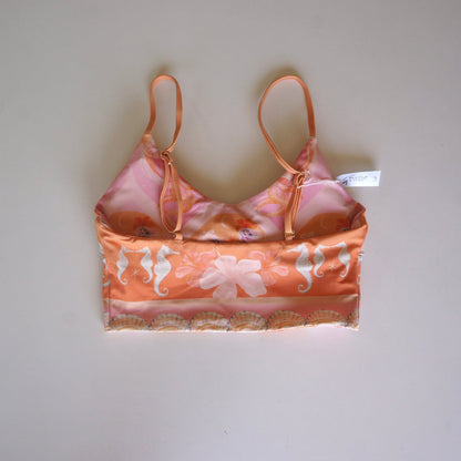 Flatlay of the back of the Chasing Rivers x Hannah Chloe Calypso crop top featuring a peach seahorse print, floral artwork, and adjustable straps on a white background.