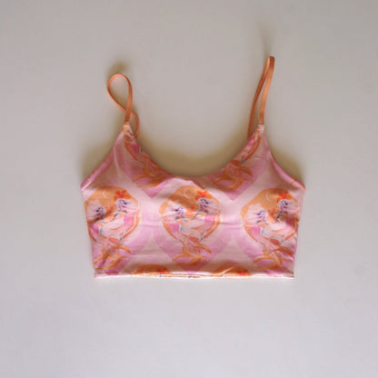 Flatlay of the Chasing Rivers x Hannah Chloe Calypso pink illustrated crop top featuring soft peach and pink feminine artwork on a white background.