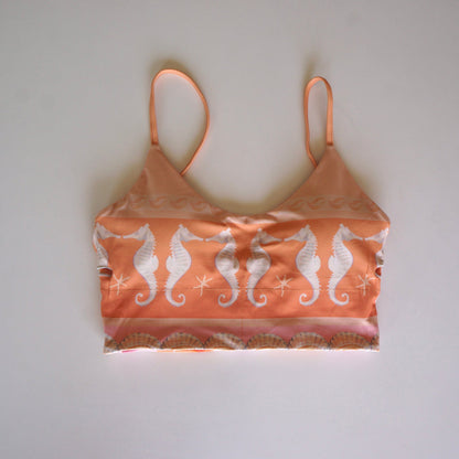 Flatlay of the Chasing Rivers x Hannah Chloe Calypso crop top featuring a peach and white seahorse print with coastal-inspired details on a white background.
