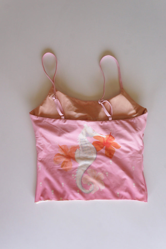 Flatlay of the back of the Chasing Rivers x Hannah Chloe pink cami, featuring a seahorse and floral illustration in soft peach and pink tones on a white background.