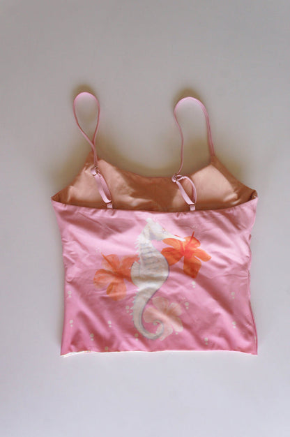 Flatlay of the back of the Chasing Rivers x Hannah Chloe pink cami, featuring a seahorse and floral illustration in soft peach and pink tones on a white background.