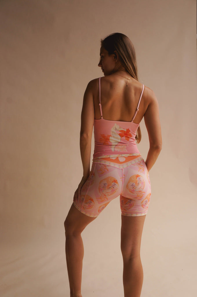 Back view of model wearing the Chasing Rivers x Hannah Chloe pink illustrated cami and bike shorts set, showing flowing feminine artwork in soft peach and pink tones.