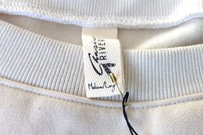 Close-up of the Chasing Rivers clothing label on the Grounded sweatshirt from the Studio Hannah Chloe collaboration, made from organic cotton.
