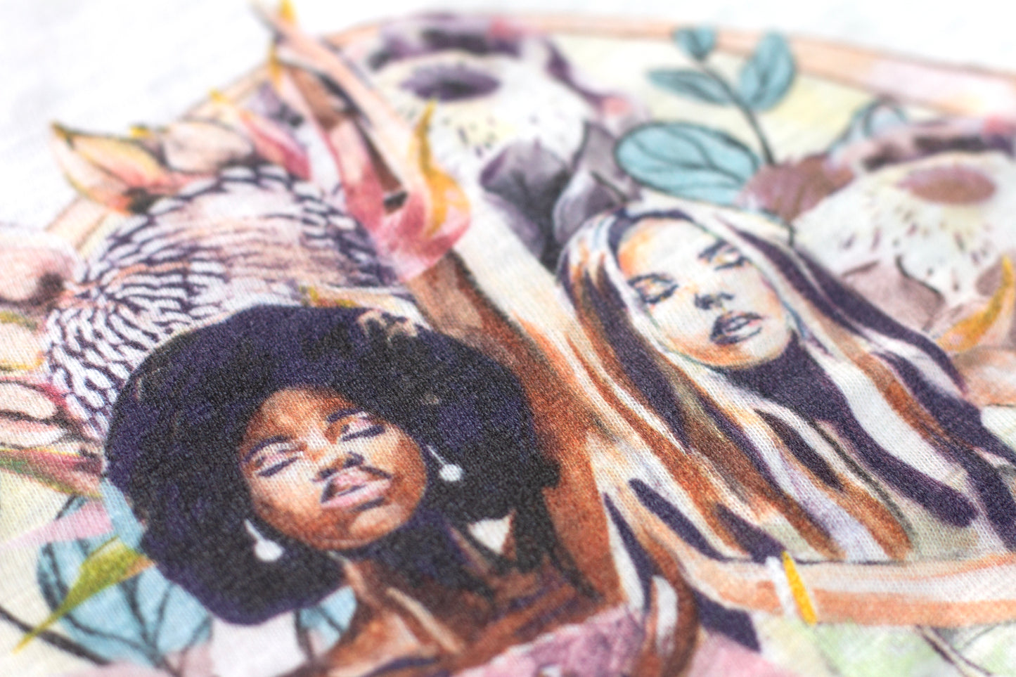 Close-up detail of the Grounded t-shirt artwork by Studio Hannah Chloe, showing two women surrounded by botanical shapes printed on organic cotton fabric.